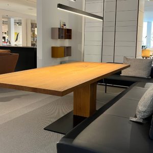 Modern office lounge with a long wooden table and a gray cushioned bench seat across from it.
