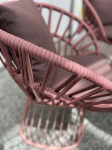 Close-up of a pink rope-woven outdoor chair, showing braided strands and curved frame.