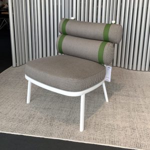 A modern round-seat chair with beige upholstery, white legs, and two cylindrical back cushions with green bands, placed on a beige carpet.
