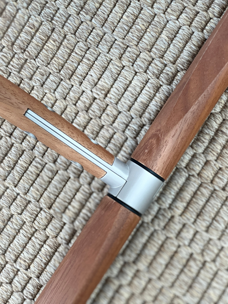 Close-up of two wooden furniture legs joined by a silver metal connector with black seals.