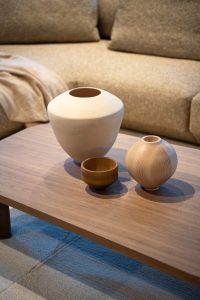 Decorative ceramic vases on a light wooden coffee table in front of a beige sofa.