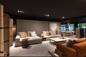 Modern showroom living room with beige sectional sofas, a white marble coffee table, and warm lighting.