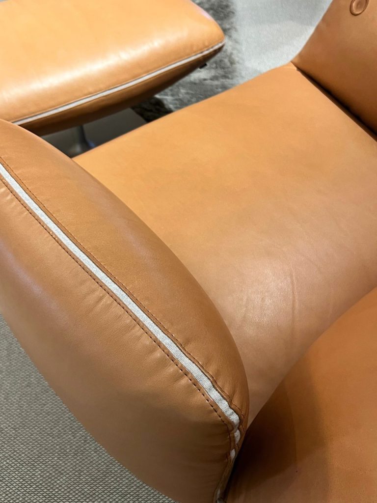 Close-up of tan leather chair cushion with a white zipper along the seam.