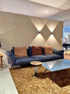 Blue sectional sofa with brown cushions on a brown shag rug in a modern showroom display.