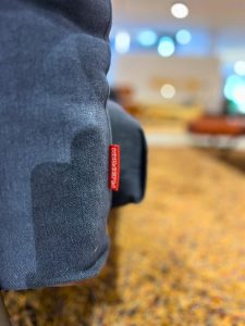 Close-up of dark blue denim fabric with a red Levi's tag, likely on a bag or backpack, with a blurred indoor background.