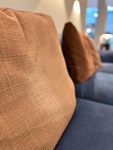 Close-up of a textured brown cushion on a blue sofa in a modern lounge area.