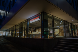 Night-time storefront with large glass windows revealing a furniture showroom inside.