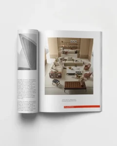 Open magazine spread showing a modern neutral-toned living room with beige sofas, chairs, and a tufted bench at the center.