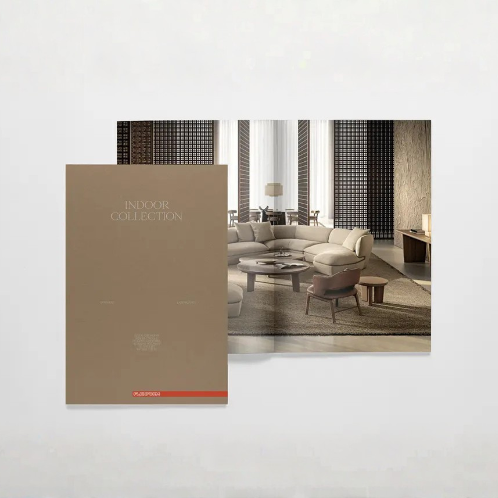 Open interior design catalog showing a beige 'Indoor Collection' cover beside a modern living room setup with a neutral-toned sectional sofa and coffee table.