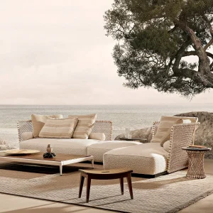 Beige wicker outdoor seating area by the sea with striped cushions and a low coffee table.