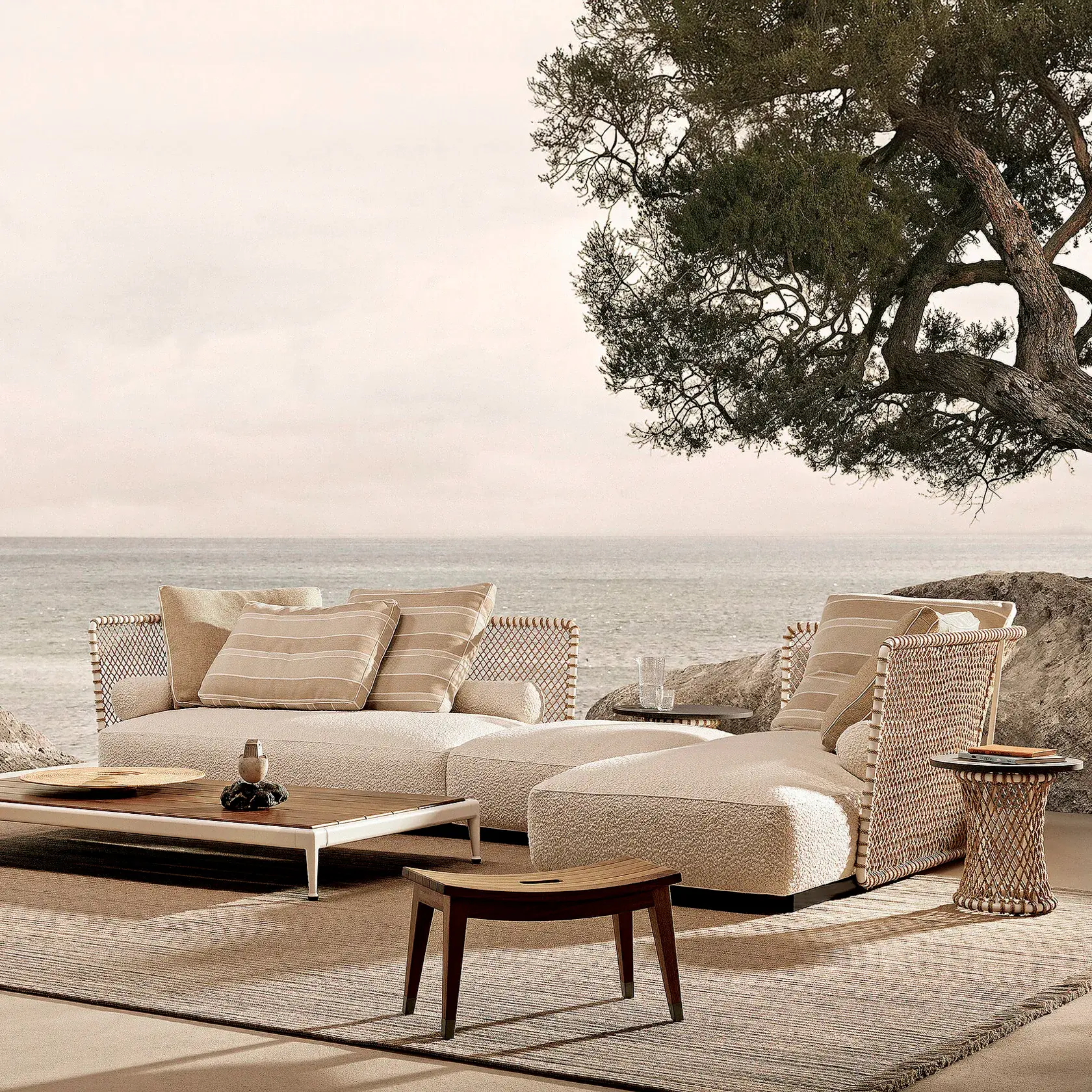 Flexform-oasis Beige wicker outdoor seating area by the sea with striped cushions and a low coffee table.