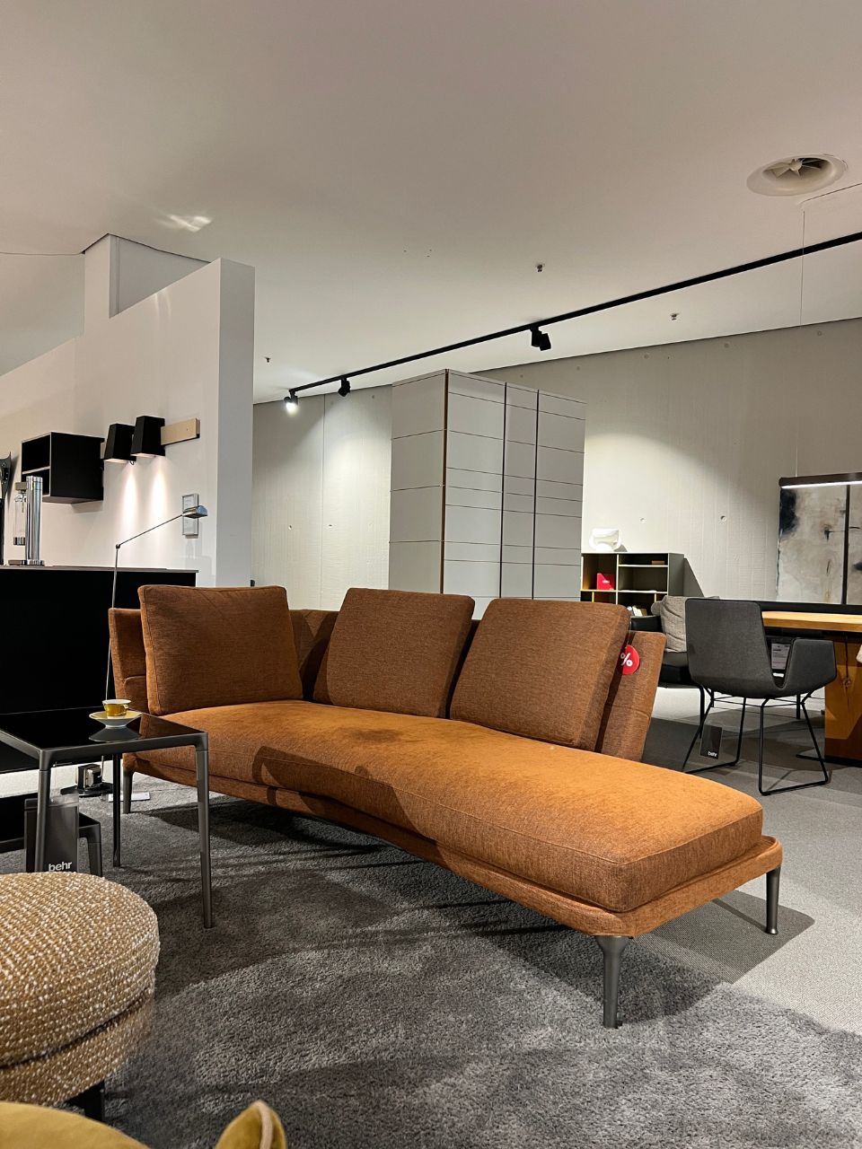 Brown modular sofa with metal legs in a contemporary showroom displaying living room furniture.