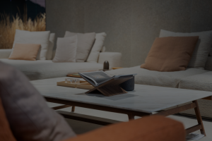 Cozy living room with a sofa and multiple neutral cushions, a wooden coffee table, and an open magazine in the foreground.