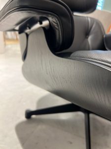 Close-up of a black leather office chair showing the curved seat and metal support on a concrete floor.