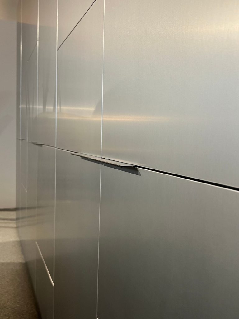 Stainless steel kitchen cabinets with slim horizontal handles, photographed from the side.