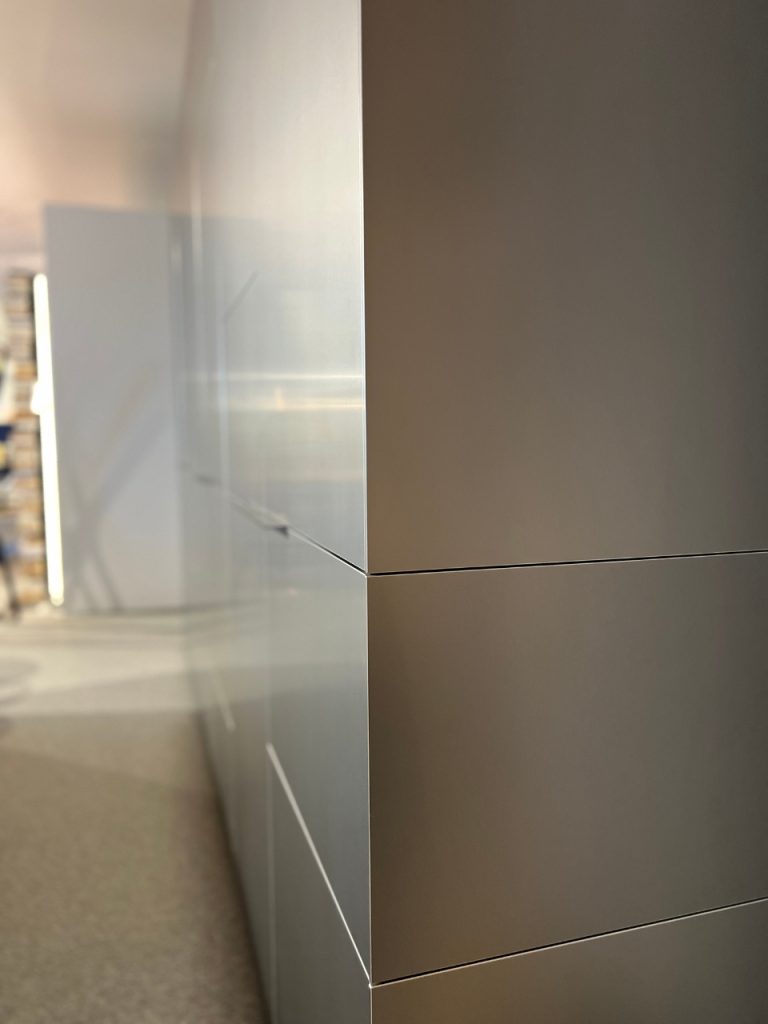 Close-up of tall gray metal cabinets with clean horizontal seam lines, viewed from a corner in an office.
