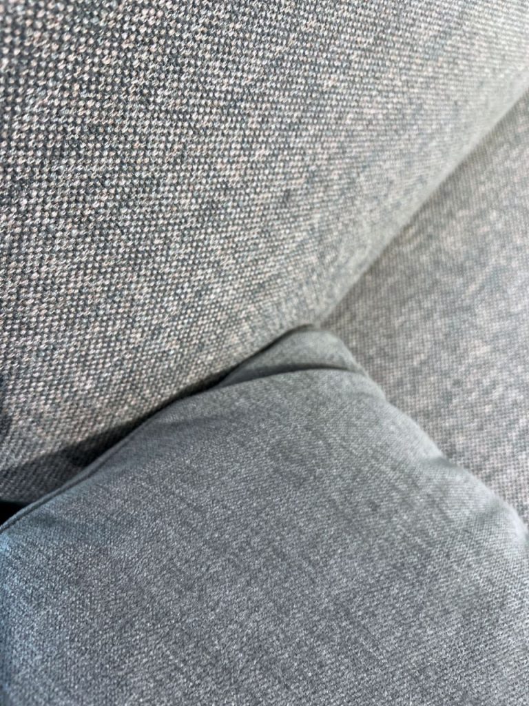Close-up of gray fabric upholstery with a seam visible on a couch.