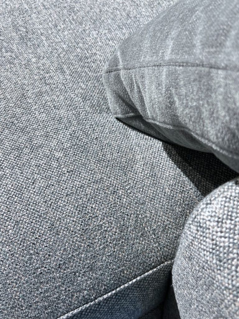 Close-up of blue denim fabric with a visible seam and fold.