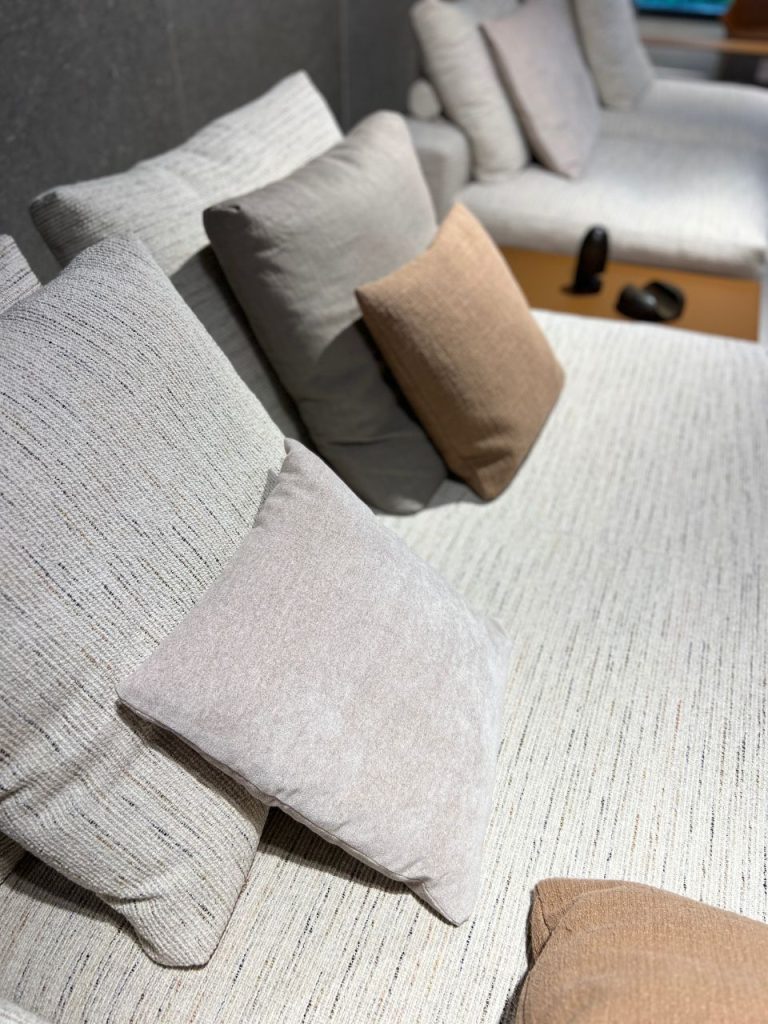 Grey sectional sofa with beige and brown throw pillows in a cozy living room setting